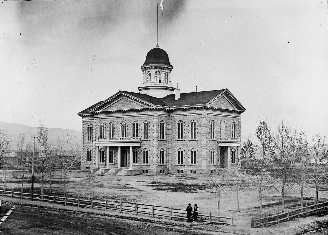 The Nevada State Capitol in Carson City photographed in 1875, a few years after its completion, with its cupola, picket fence, and young trees. Nevada Historical Society, public domain, via Wikimedia Commons.