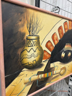 A framed abstract painting featuring a large black bird-like silhouette, a gold patterned vase, orange geometric shapes, and a striped object on a yellow and brown background, photographed indoors on a metal grid surface.