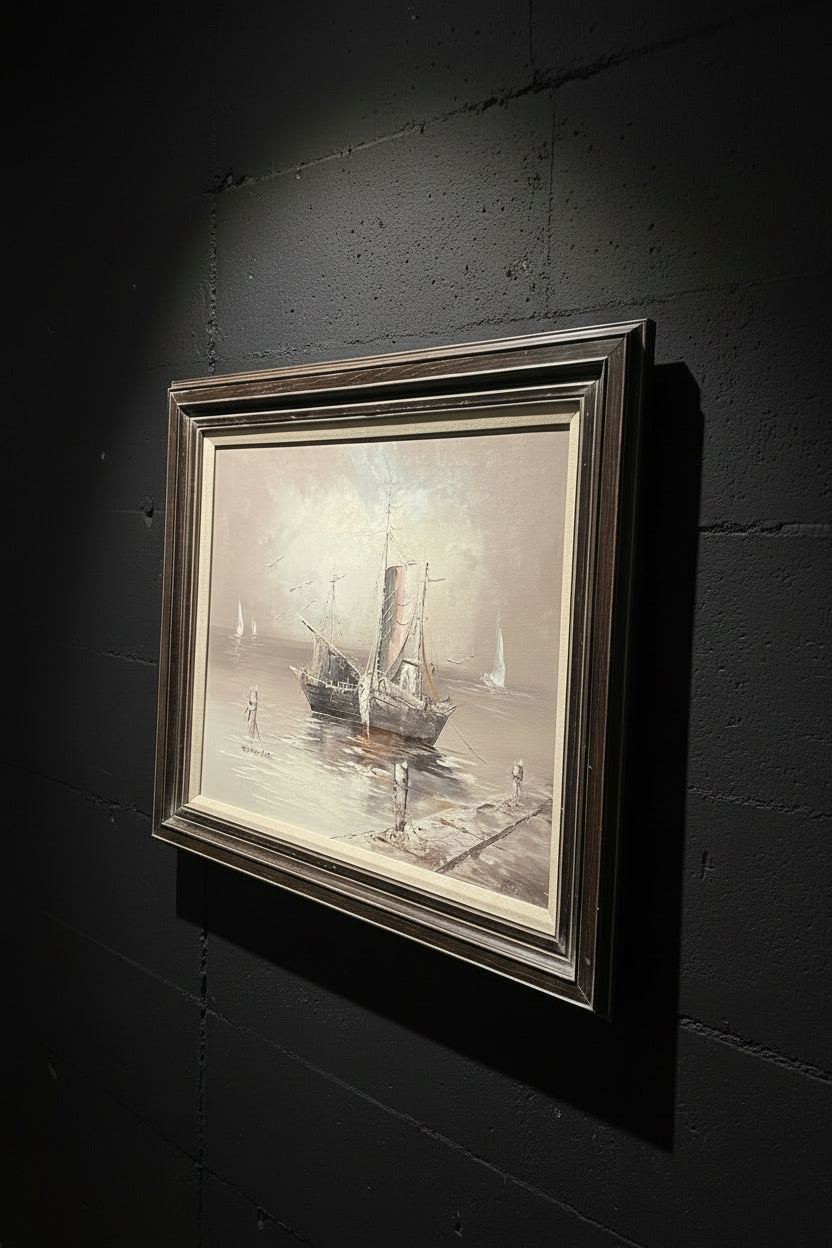 Framed painting of a ship on a dock with a decorative metal stand in the background.