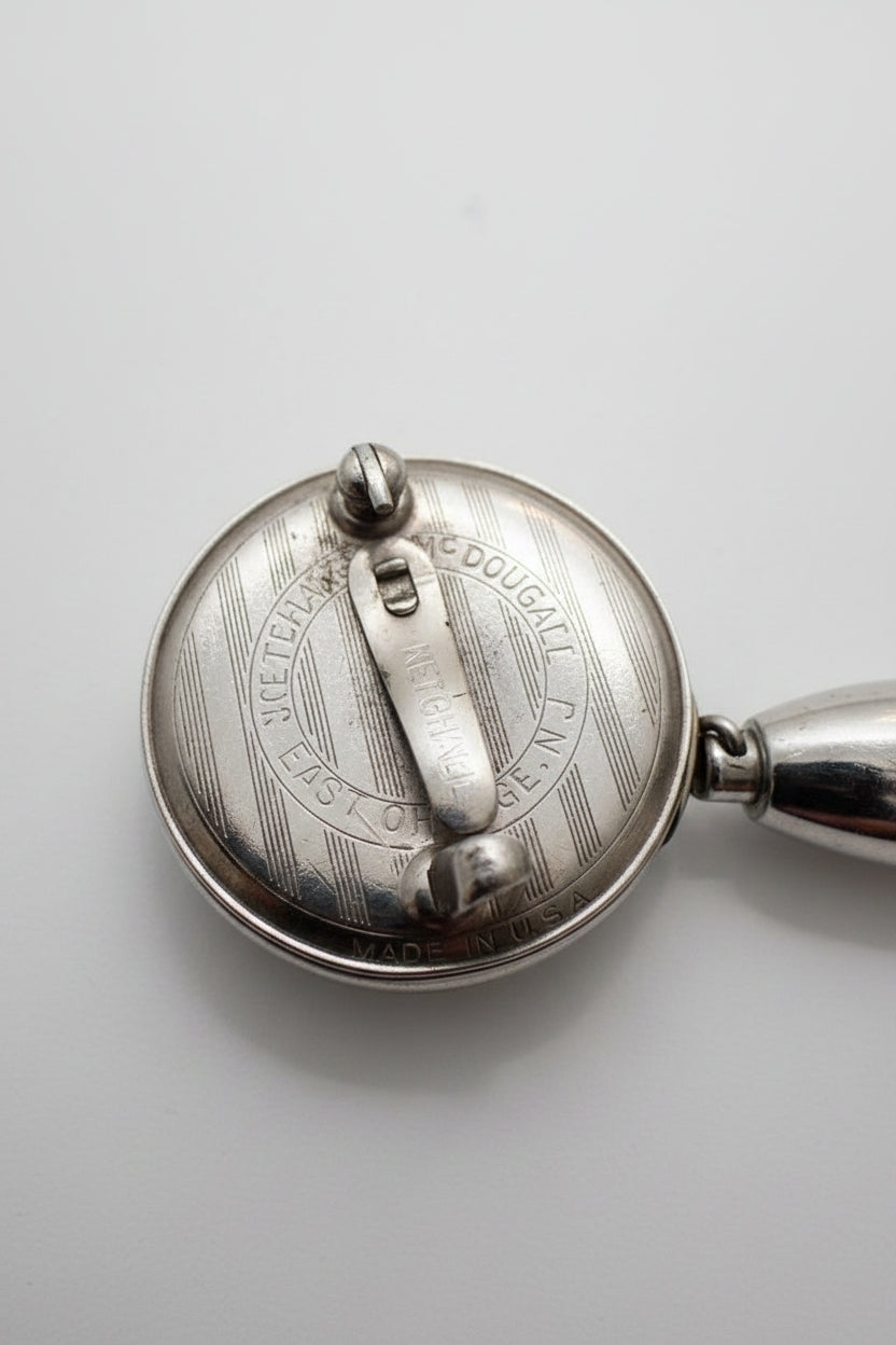 Close-up of a silver metal object with engraved text on a white surface