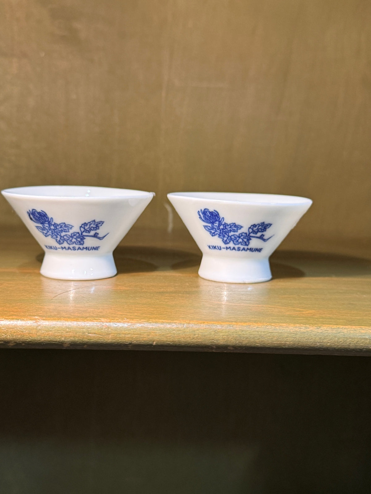 Pair of Kiku-Masamune Sakazuki, Footed Porcelain Sake Cups Printed in Cobalt with a Chrysanthemum Spray, Marked Made in Japan and 菊正宗 — Brewery Cups from a House Brewing Since 1659, c. 1955–1970